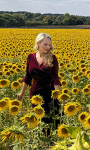 Katya in a deep red velvet dress in a field of sunflowers